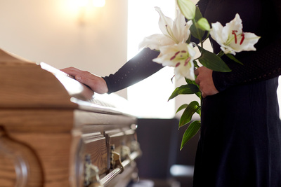 woman holding flowers over casket